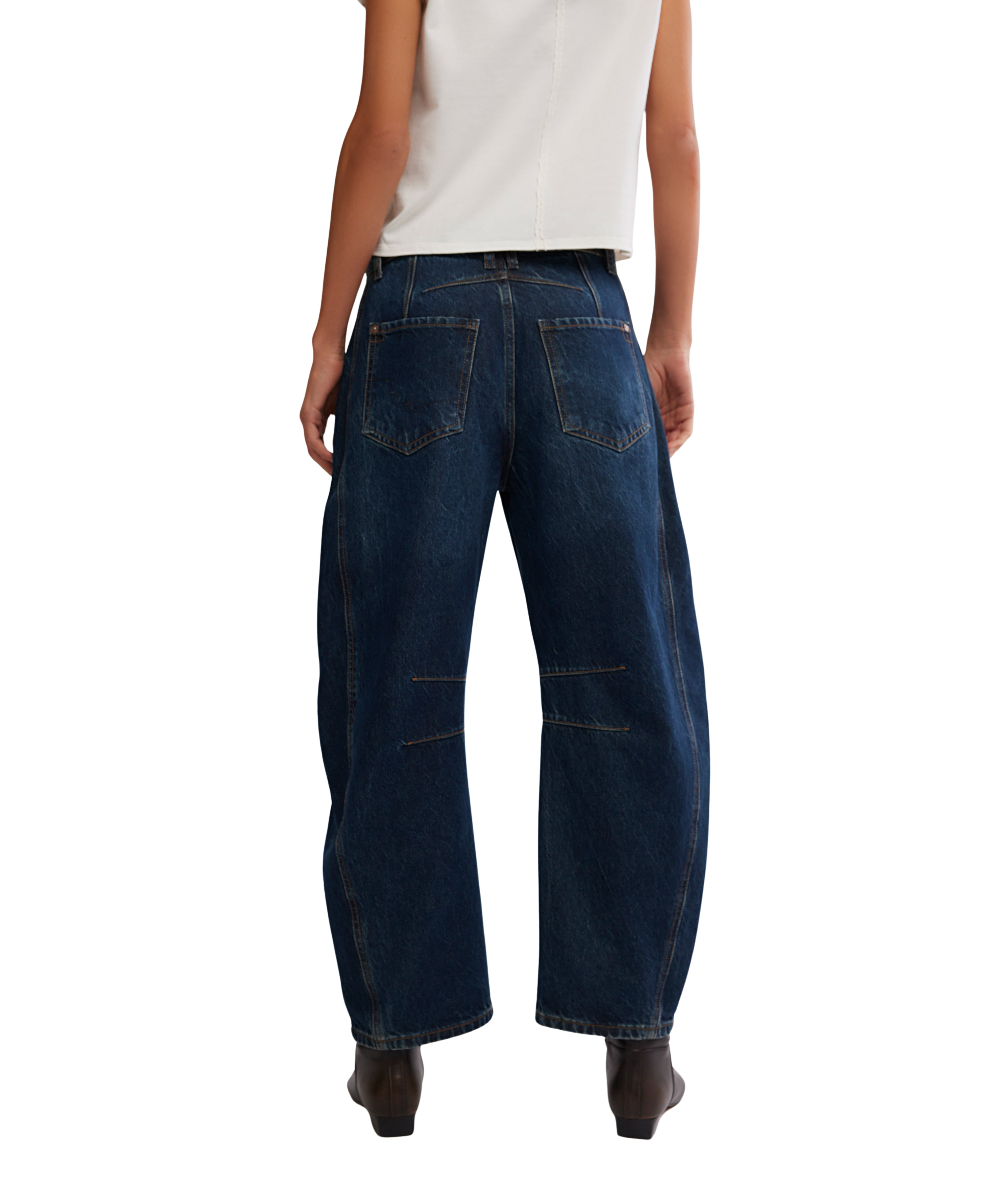 Back view of dark denim Free People Good Luck Maker Barrel Jeans styled with a white top and brown boots
