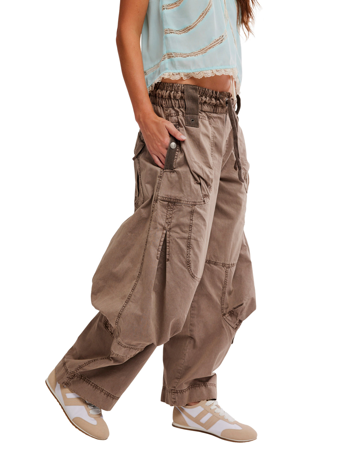 Side view of taupe Free People Onset Parachute Pant with multiple pockets and casual sneakers on white background