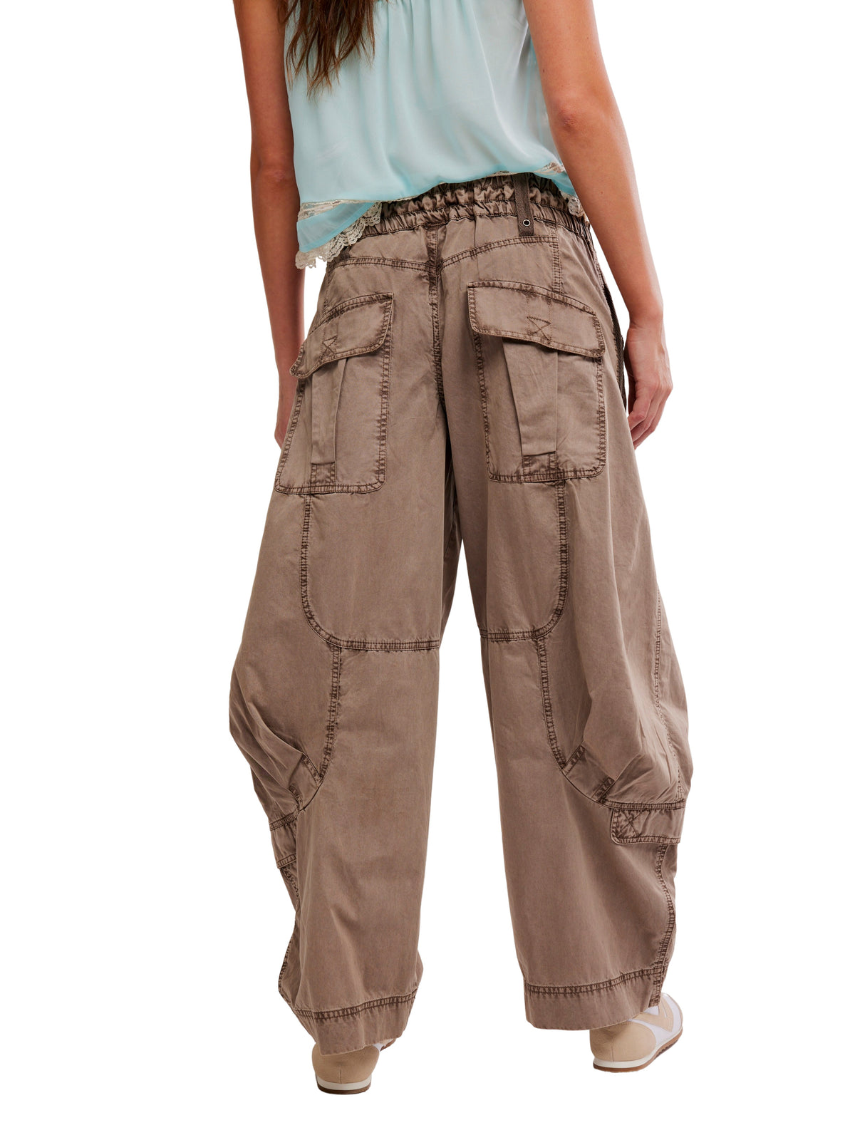 Loose-fitting brown cargo pants with large pockets and detailed stitching, paired with beige shoes and a light top.