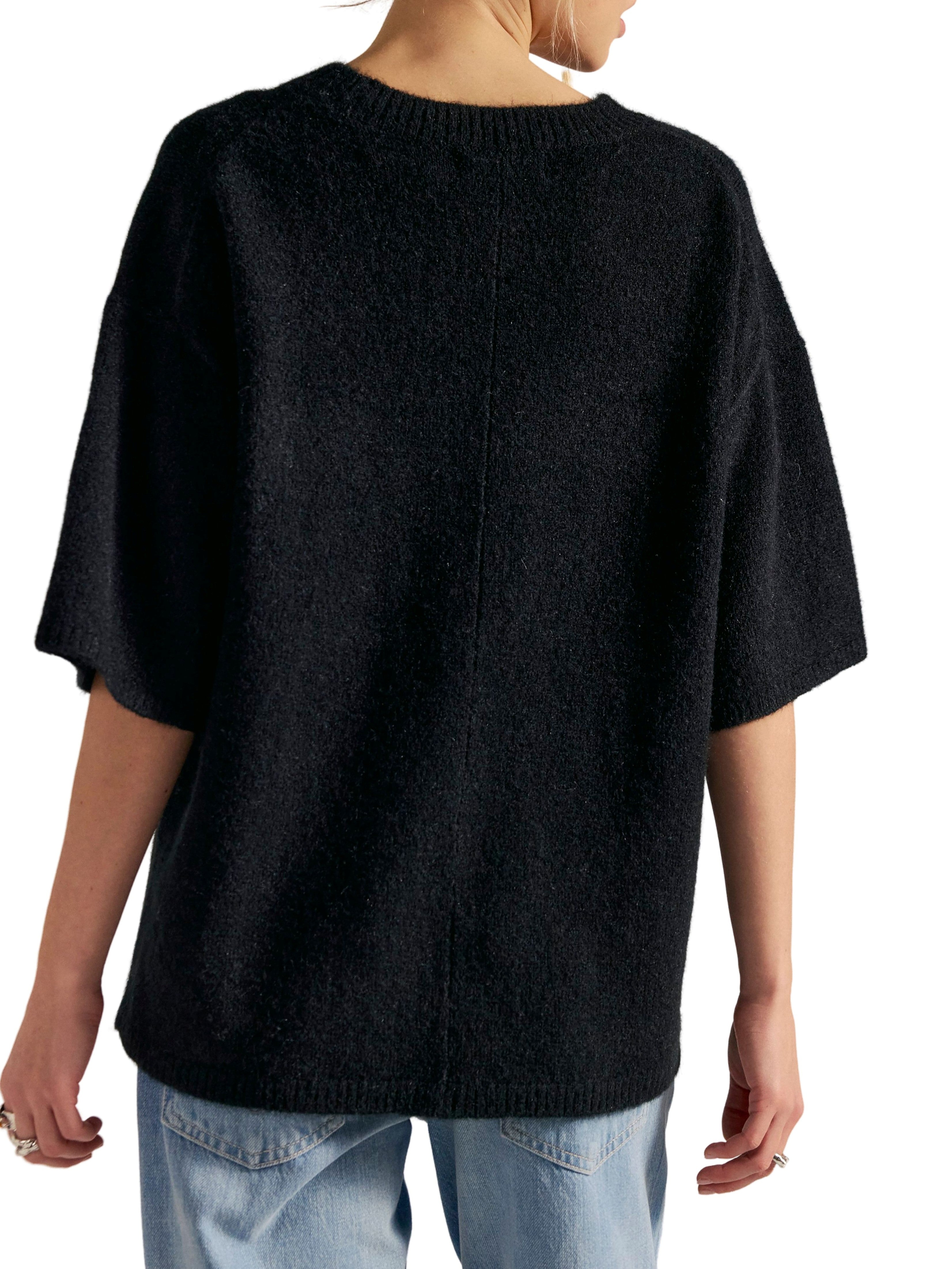 Black short-sleeve knitted sweater with a round neckline paired with light blue denim jeans from the back view.