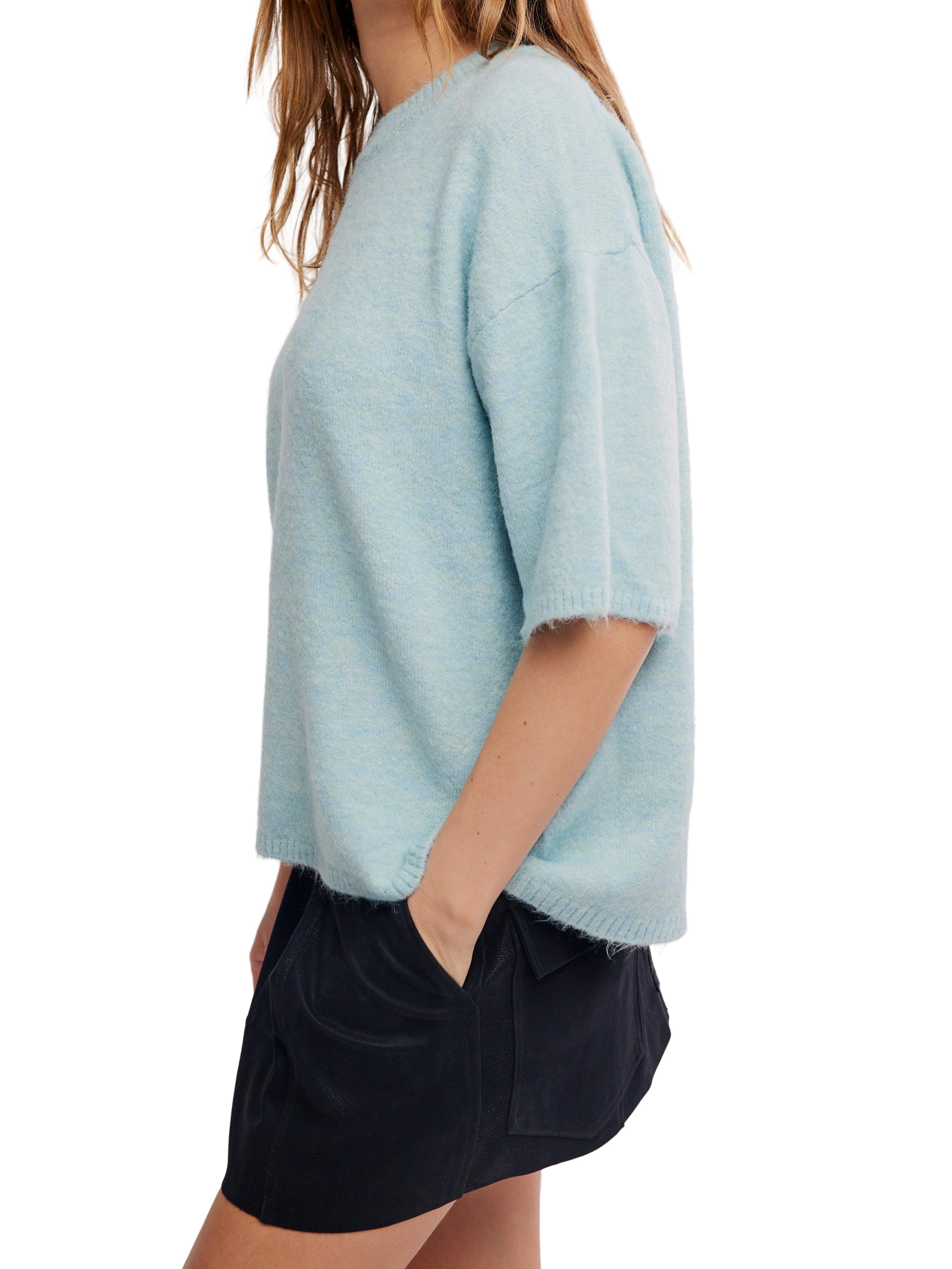 Light blue short-sleeve knit sweater paired with a dark navy skirt against a white background.