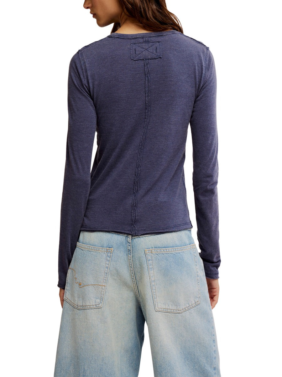 Back view of navy Free People Nova Long Sleeve Tee paired with light wash denim jeans on model.