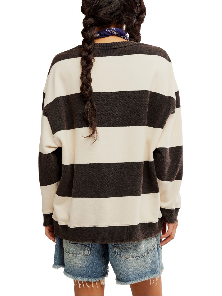 Back view of a model in a cream and dark brown striped sweater with distressed denim shorts