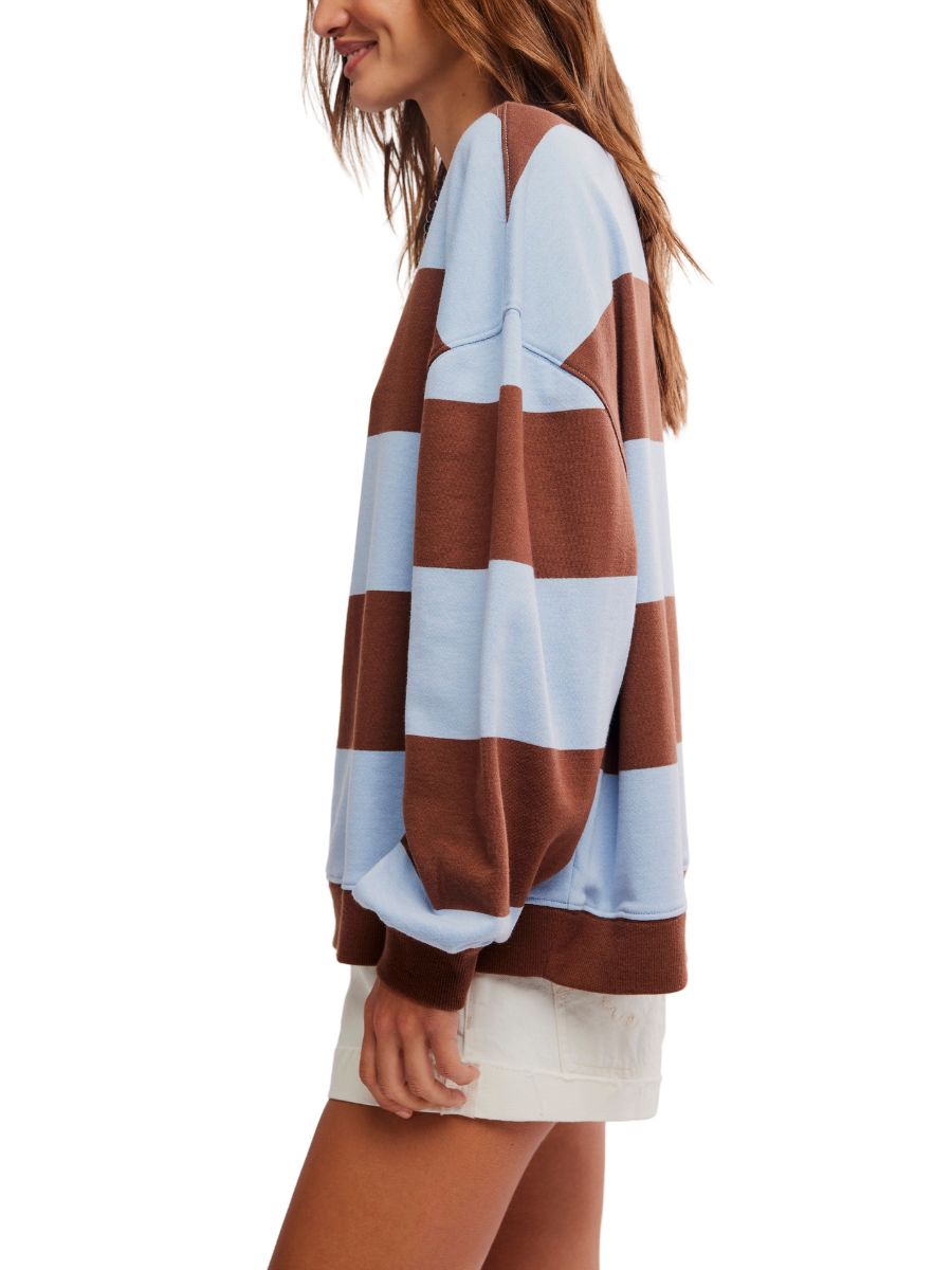 Side view of a person wearing a loose striped sweater in light blue and brown with white shorts