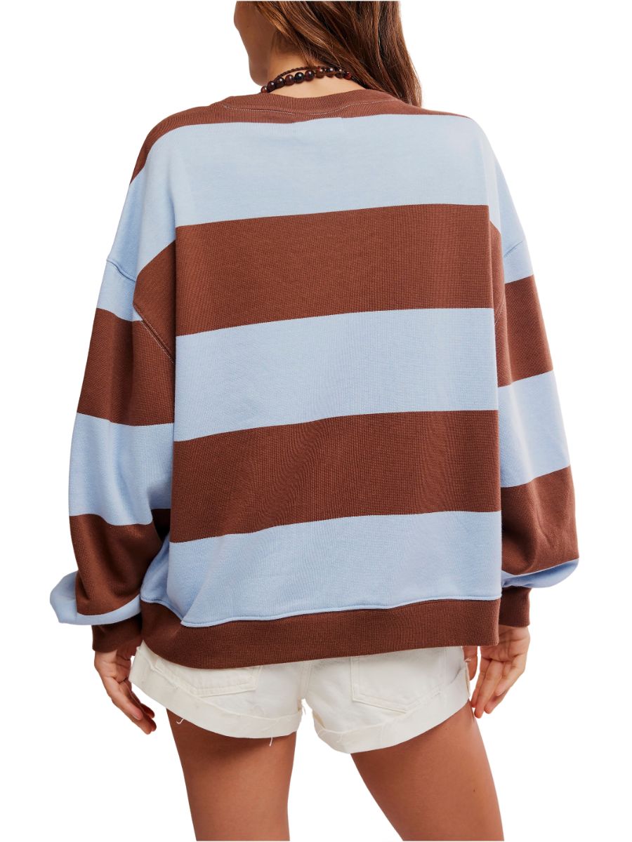Back view of person wearing oversized light blue and brown wide striped sweater with white shorts and beaded necklace
