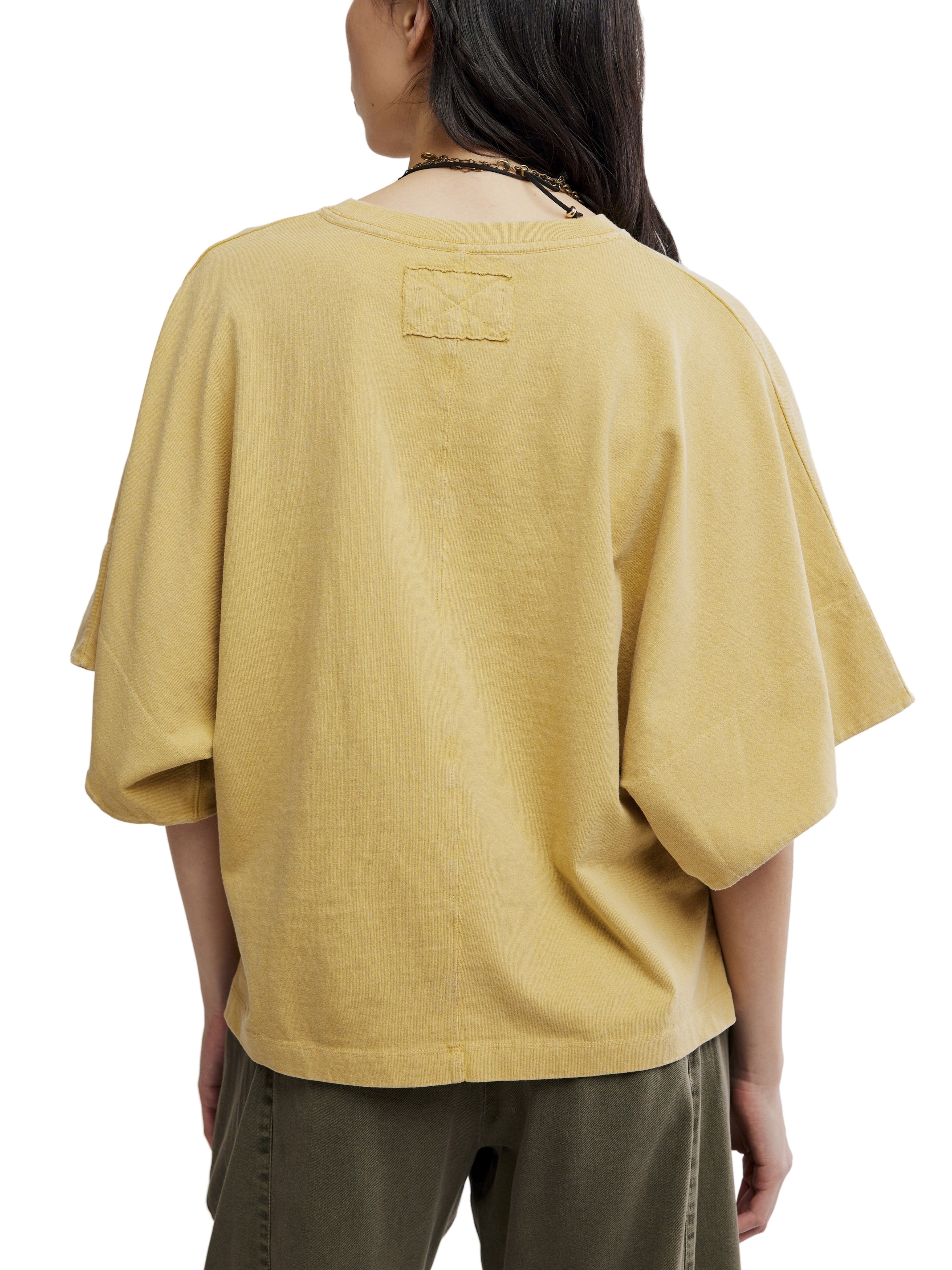 Back view of Free People Atlas Dolman Crew Top in muted gold, styled with casual green pants.