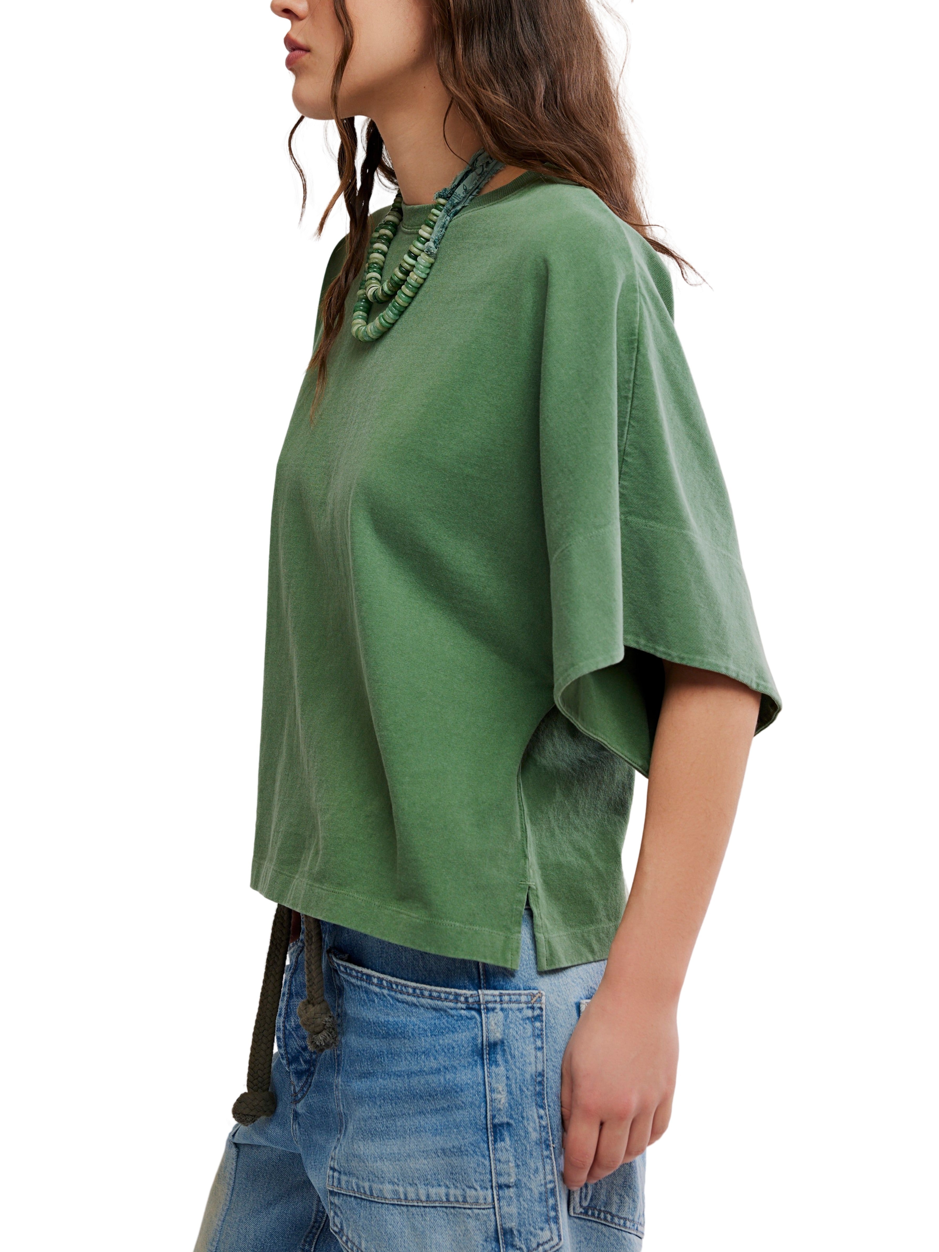 Green short-sleeve top with wide sleeves paired with blue denim patchwork pants and a green beaded necklace