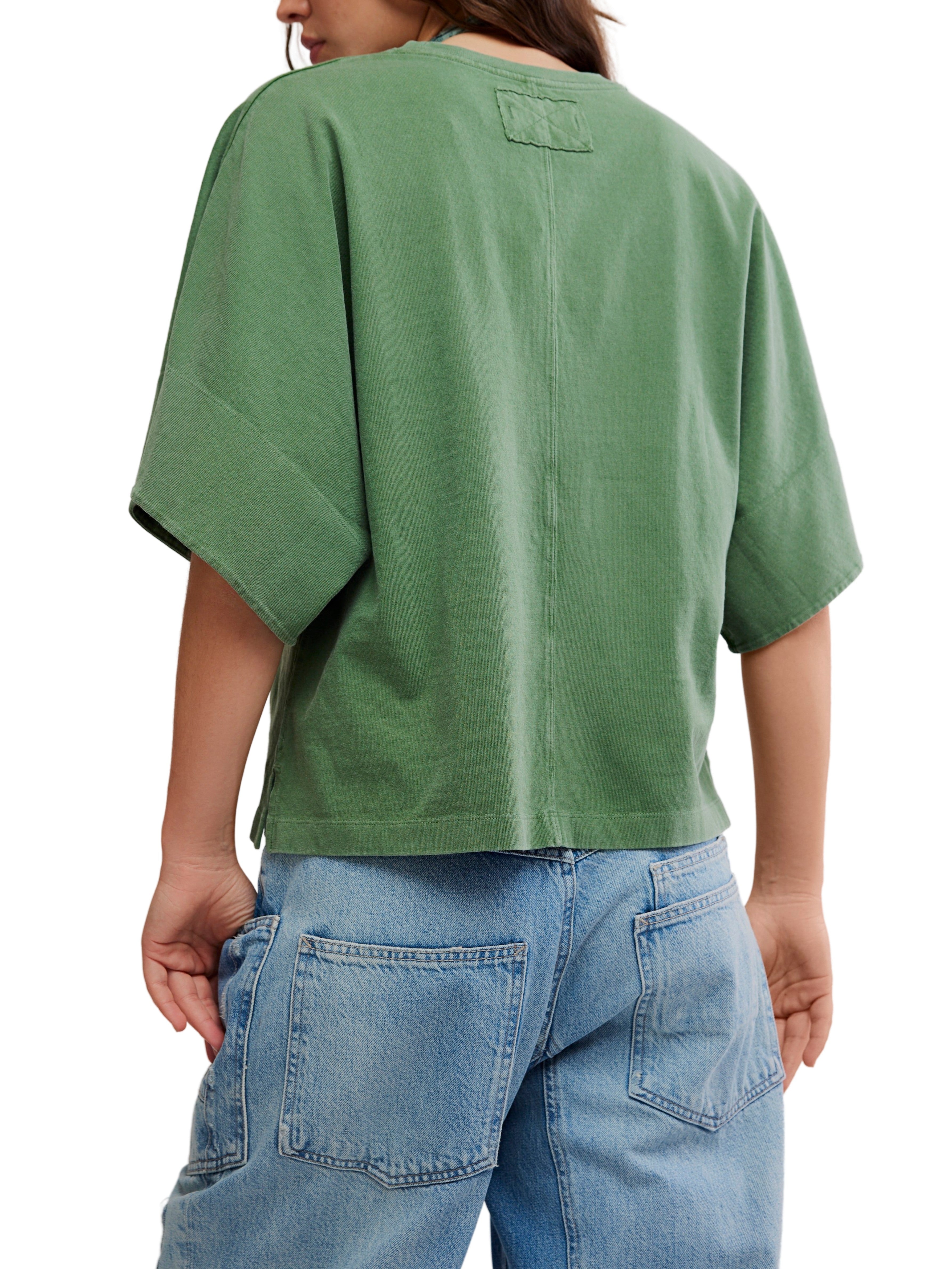 Green oversized short-sleeve top paired with light-wash denim shorts featuring large back pockets.