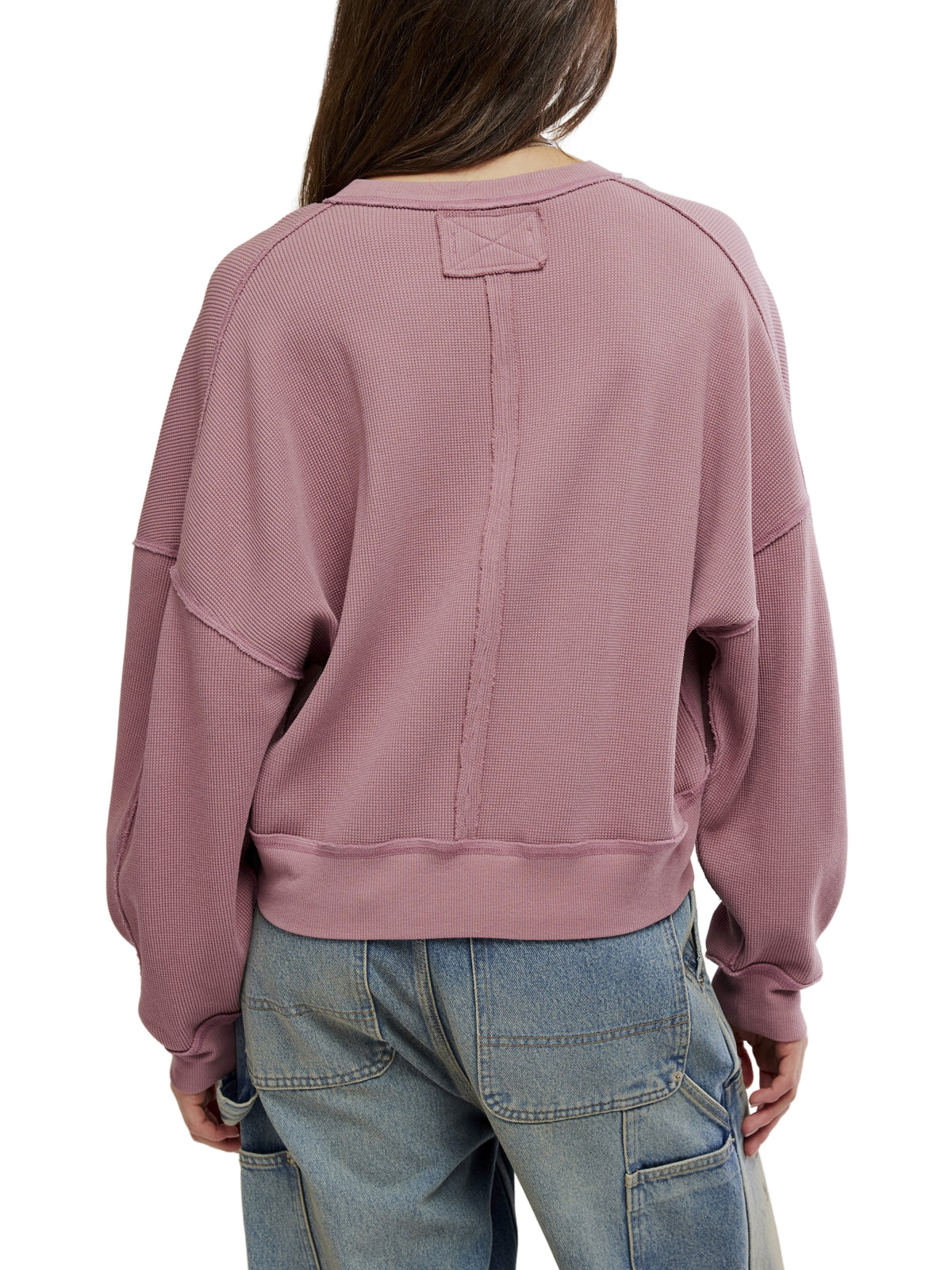 Back view of a mauve sweatshirt with seam details and blue jeans