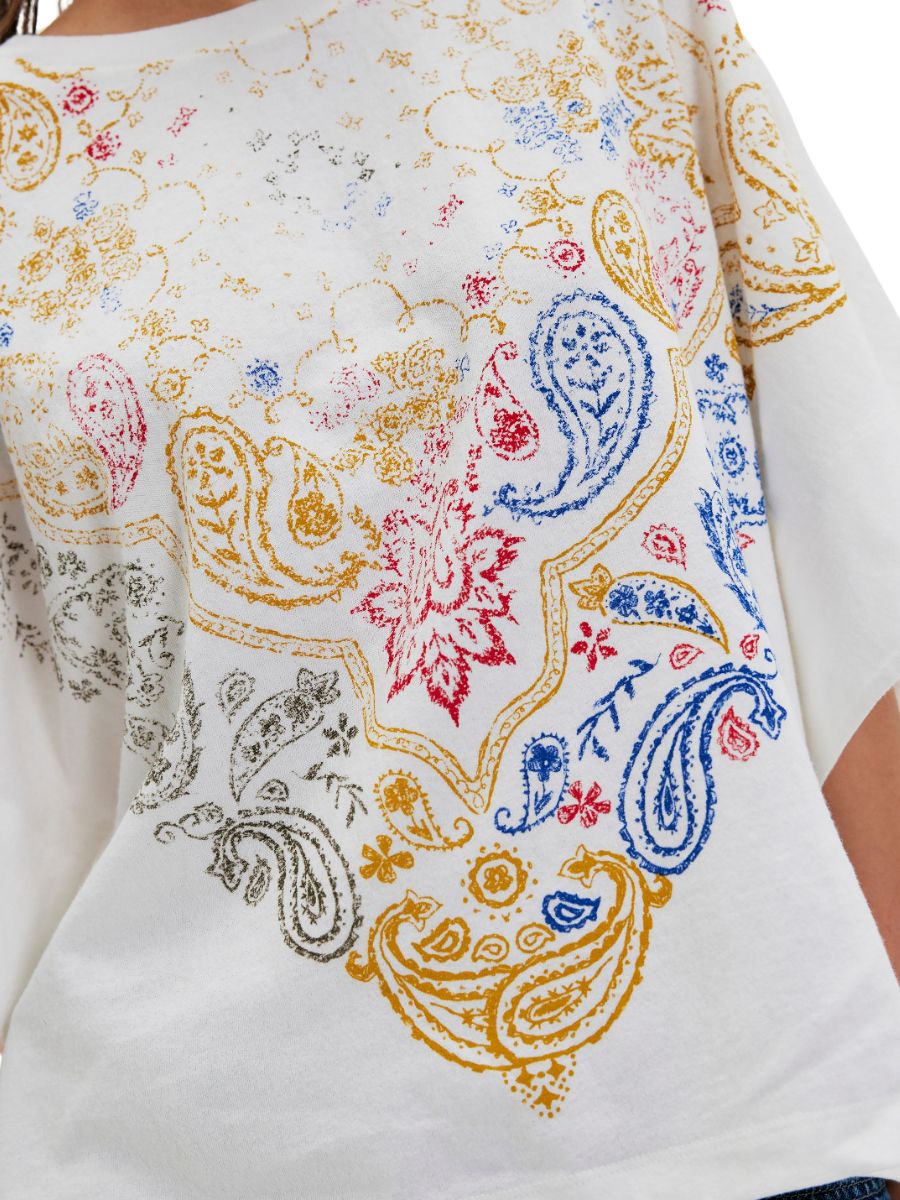 Close-up of a white top with colorful paisley and floral patterns in red, blue, yellow, and gray tones.