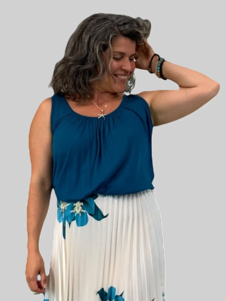 Blue sleeveless top with bubble hem and relaxed fit by Plum Loco paired with a white floral pleated skirt