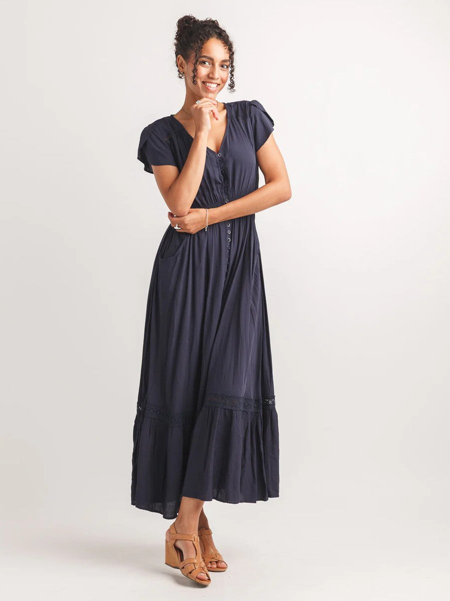 Papillon Solid Button Front Maxi Dress in navy blue with short sleeves and a flowy skirt paired with tan wedge sandals