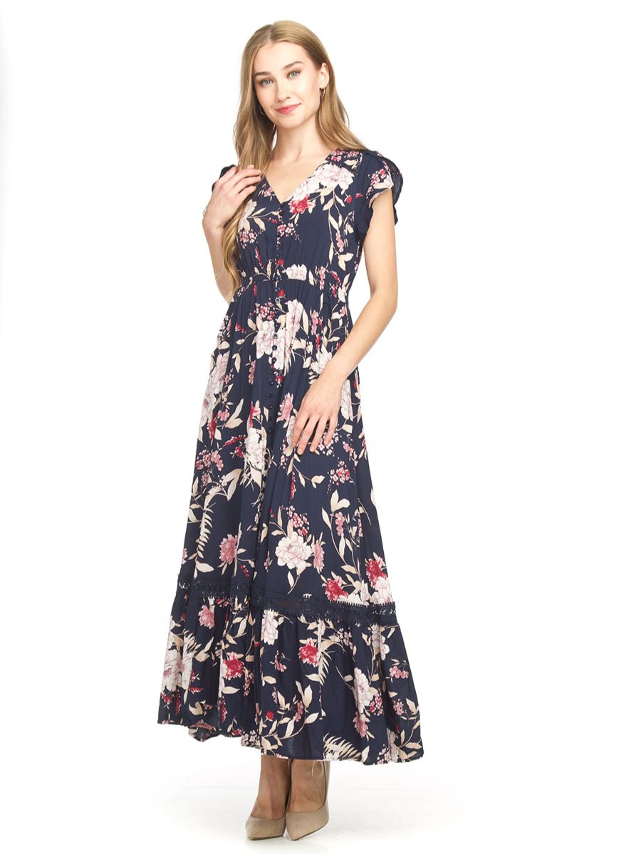 Papillon Maxed Out Baby Maxi Dress in navy with floral print, cap sleeves, and tiered hem styled with neutral heels
