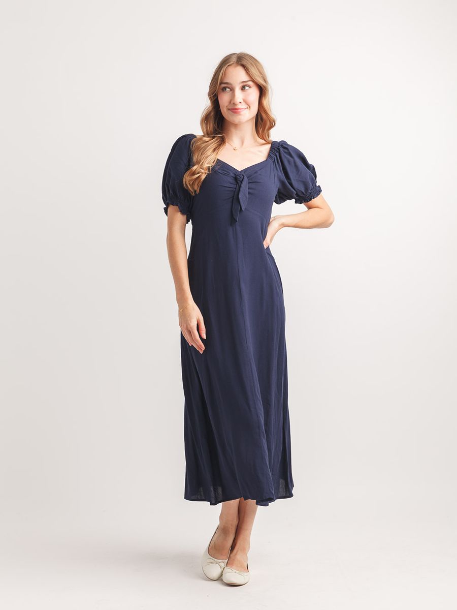 Papillon Bunny Tie Dress in navy with puff sleeves and tie detail, styled with white ballet flats by Papillon.