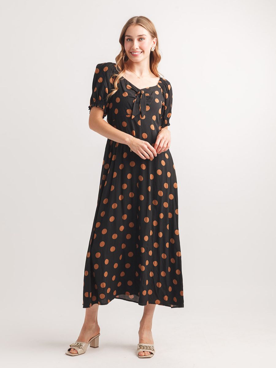 Black midi dress with brown polka dots, short sleeves, and a tie-front neckline paired with beige heeled sandals.