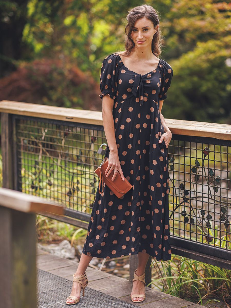 Elegant black and brown polka dot midi dress with bunny tie detail from Papillon, styled with neutral accessories outdoors.