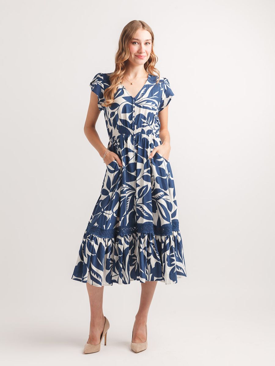 Navy and white floral print midi dress with V-neck, short sleeves, pockets, and ruffled hem on a model.