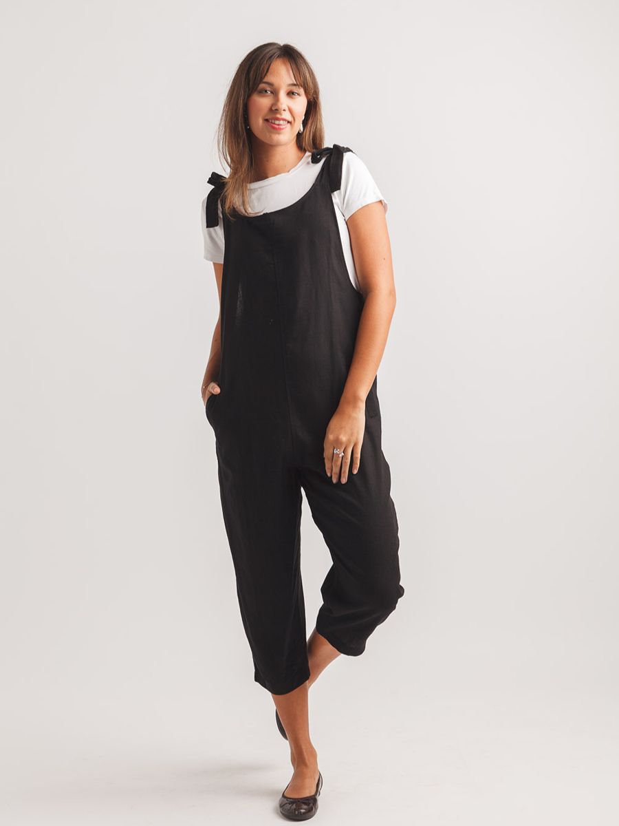 Black Papillon Free Me Tie Shoulder Jumpsuit styled with white short sleeve top and flats by Papillon brand.