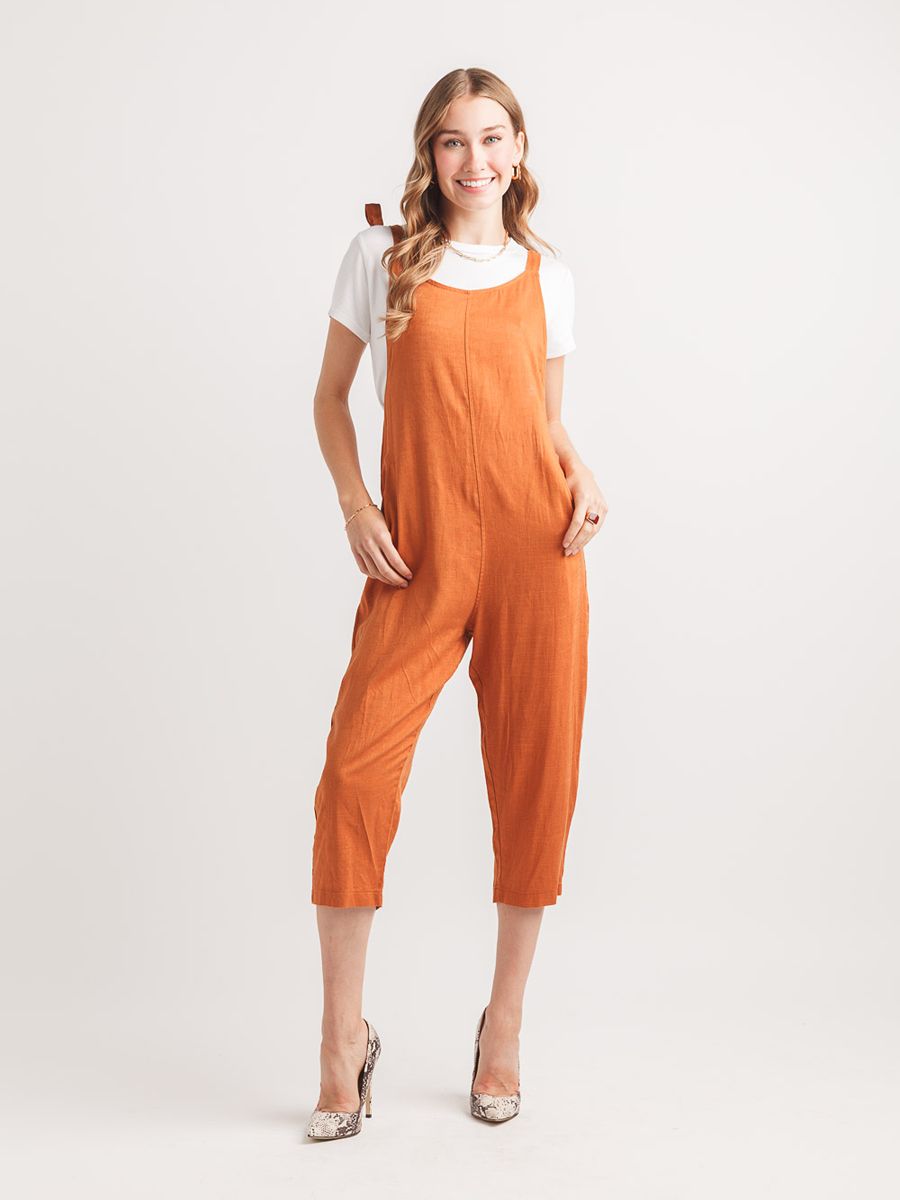 Papillon Free Me Tie Shoulder Jumpsuit in rust orange styled with a white top and neutral high heels by Papillon.