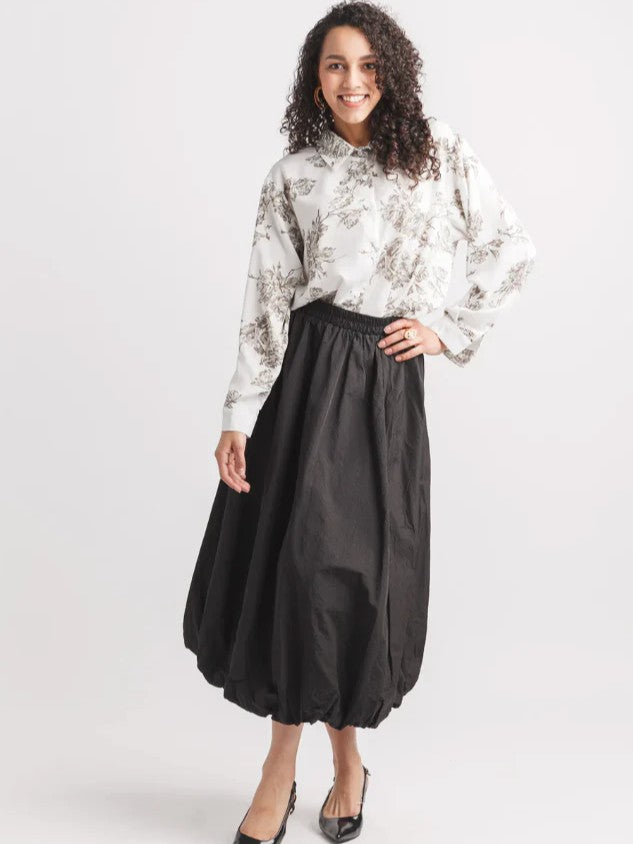 Papillon Kiki Balloon Midi Skirt in black paired with a floral print blouse, styled with black heels.