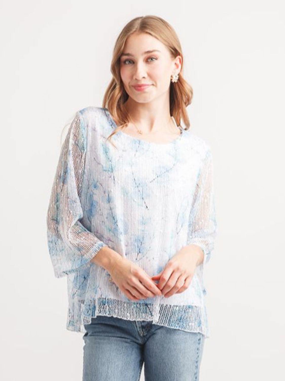 Papillon Open Knit Floral Overlay Top in light blue with sheer knit floral design and relaxed fit on model against white background