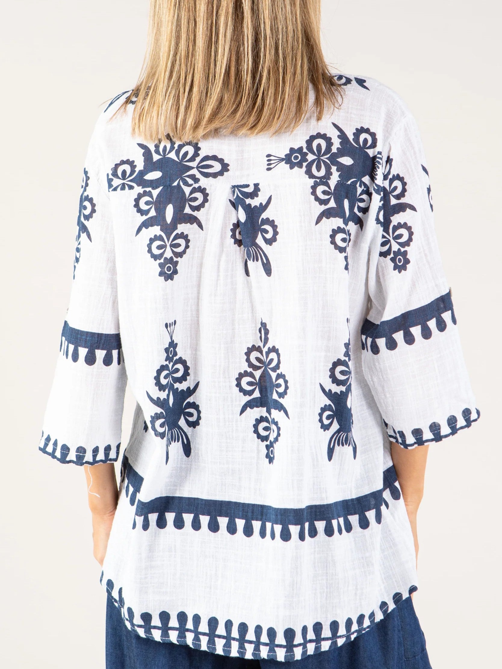 White lightweight top with navy blue floral and geometric embroidery on back and sleeves