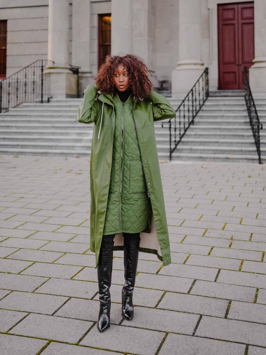 Model outdoors wearing MERNINI/ROCK RAIN INC Mernini Petite 42” Length Waterproof Raincoat in olive green outerwear.