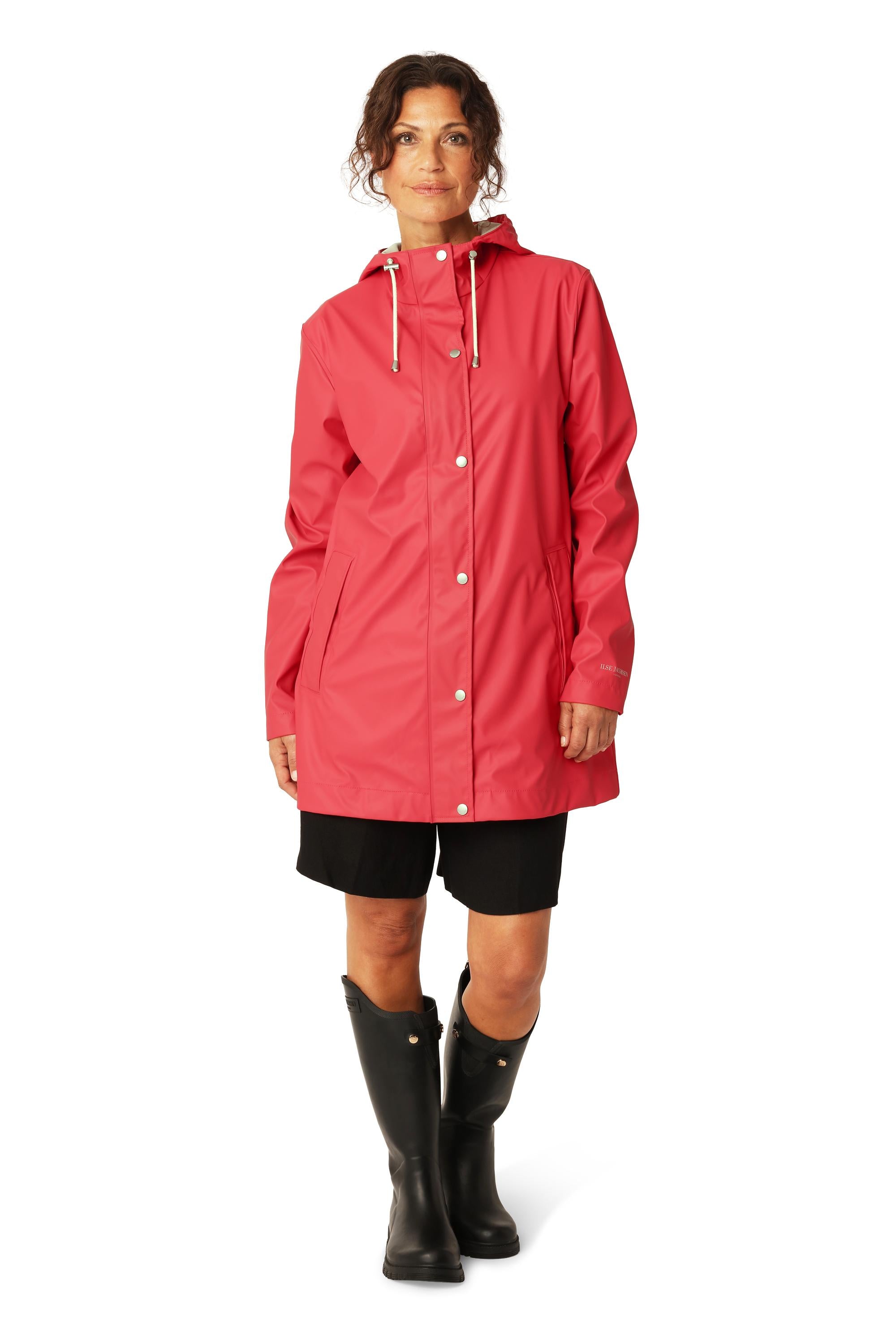 Ilse Jacobsen Rainy Days Waterproof Hooded Jacket in coral red worn with black shorts and rubber boots