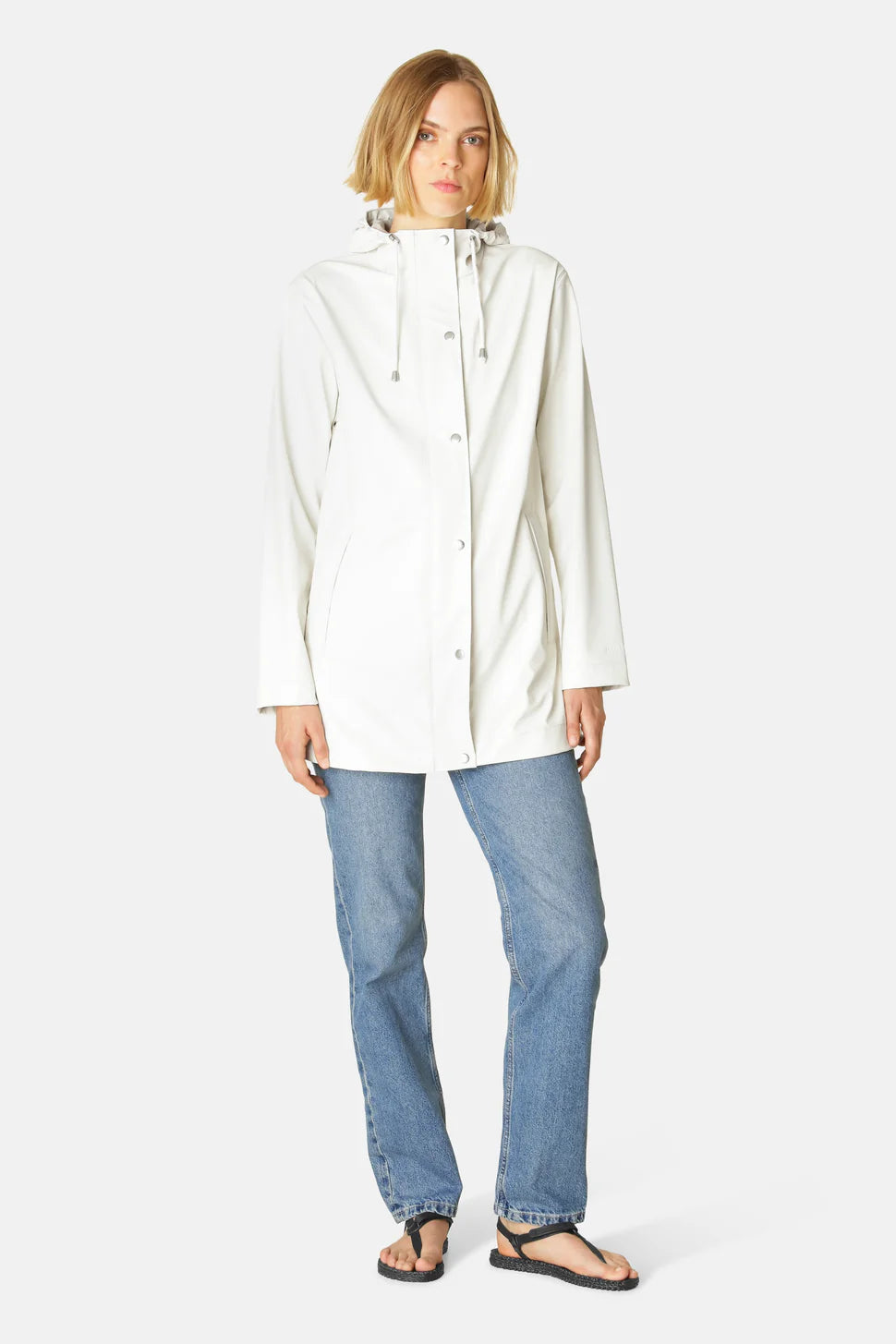 Light cream Ilse Jacobsen Rainy Days Waterproof Hooded Jacket paired with blue denim jeans and black sandals.