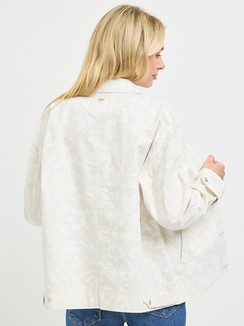 Light off-white jacket with subtle floral pattern shown from the back paired with blue denim jeans.