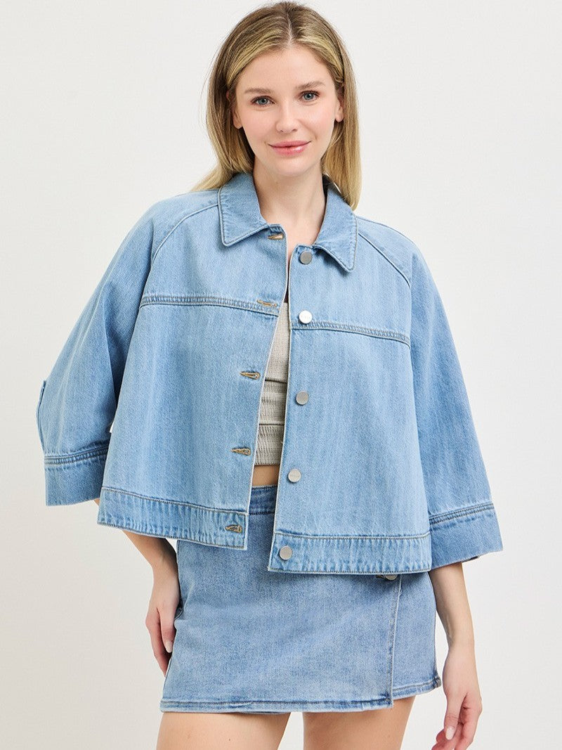 Light blue denim Cape Sleeve Denim Jacket by Risen with button front and wide sleeves, styled with matching denim skirt.