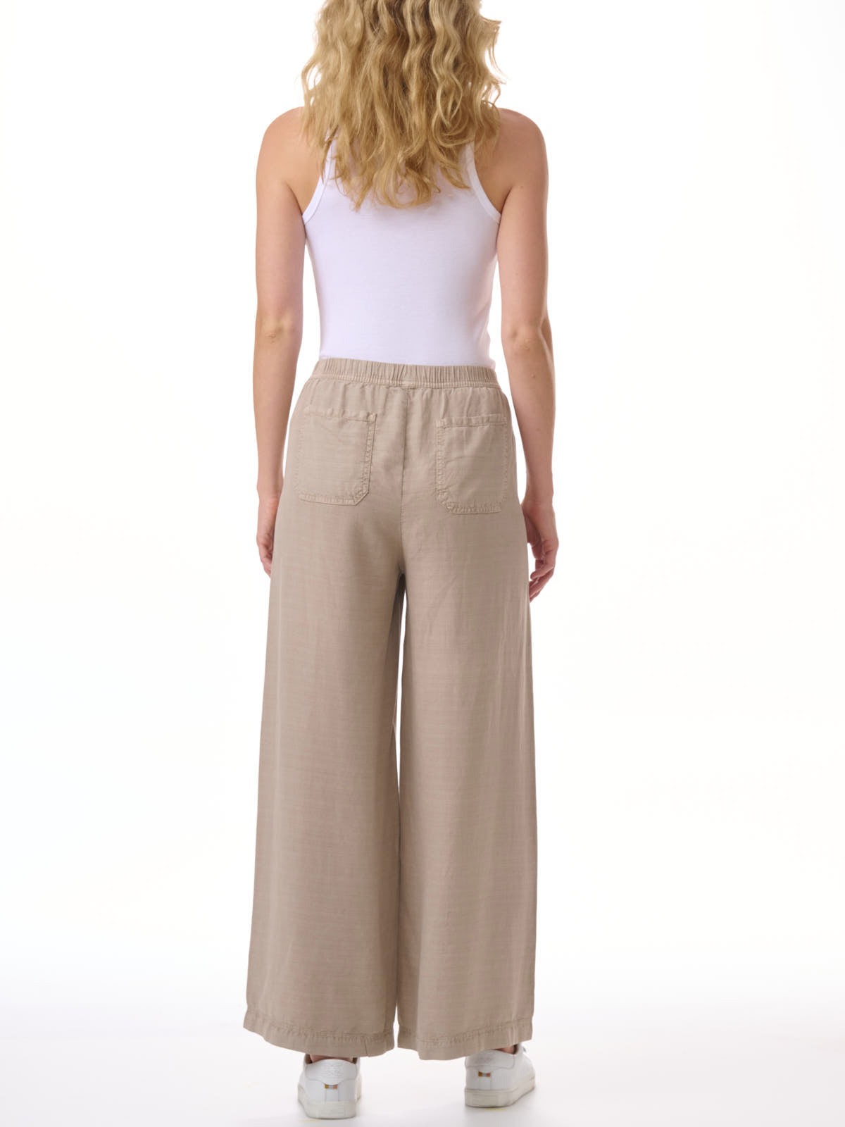 Back view of Splendid Angie Linen Blend Palazzo Pant in beige, styled with a white sleeveless top and white sneakers.