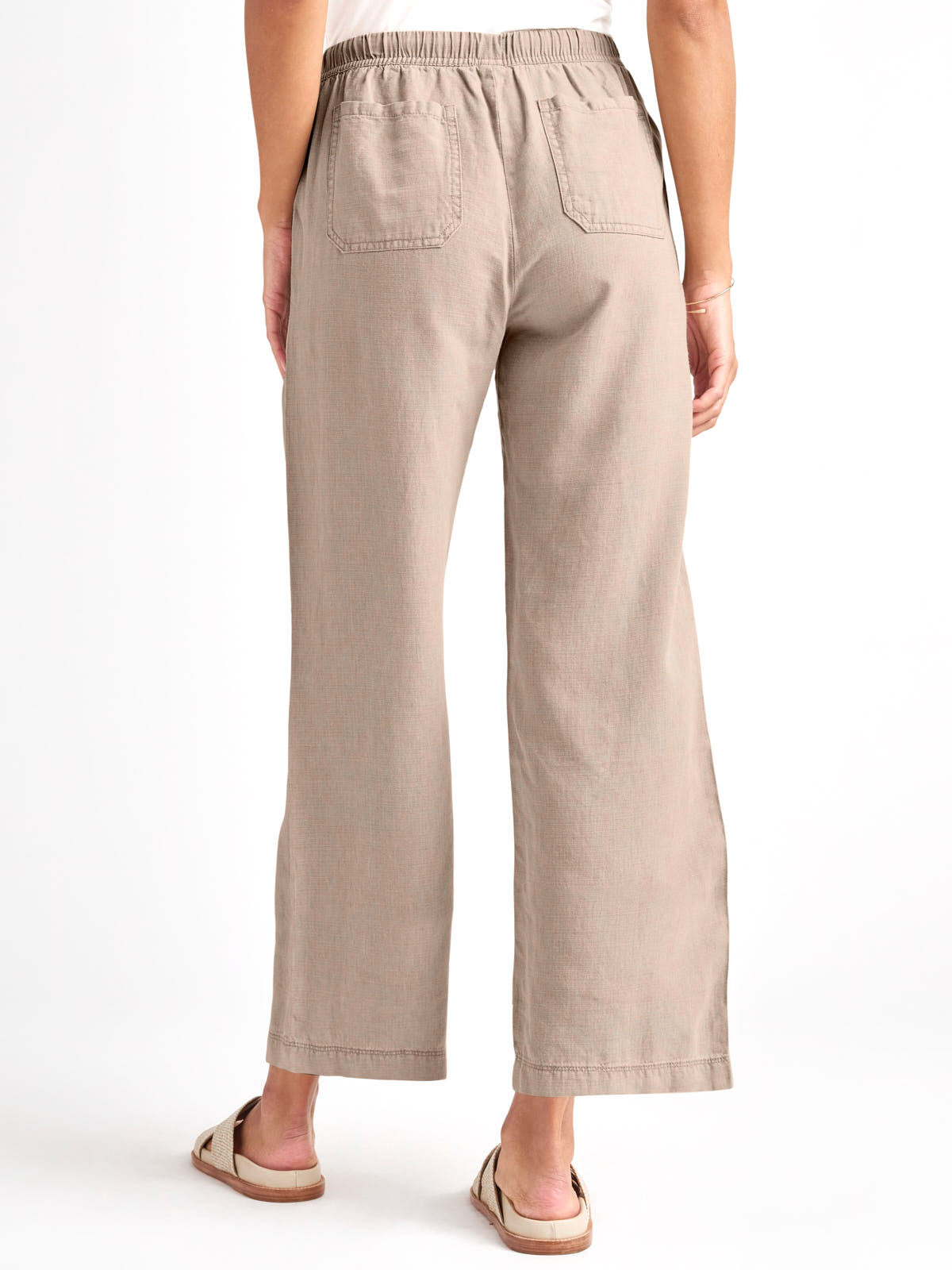 Beige wide-leg pants with an elastic waistband and back patch pockets worn with slide sandals.