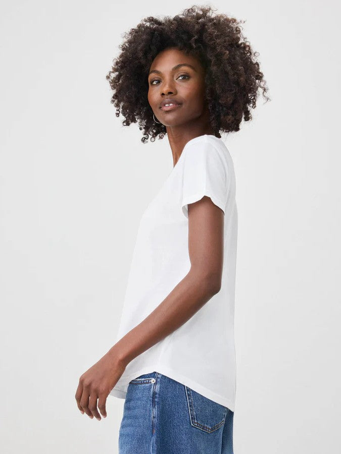 Side view of a person with curly hair wearing a plain white short-sleeve top and blue denim jeans against a plain background