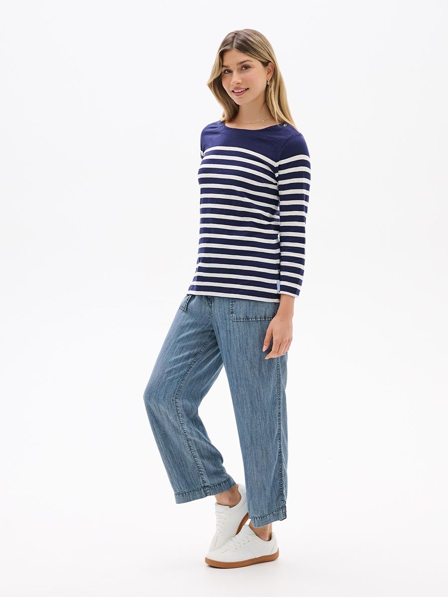 Model dressed in a navy and white striped Hatley Breton Button Long Sleeve Top paired with casual denim pants and white sneakers.