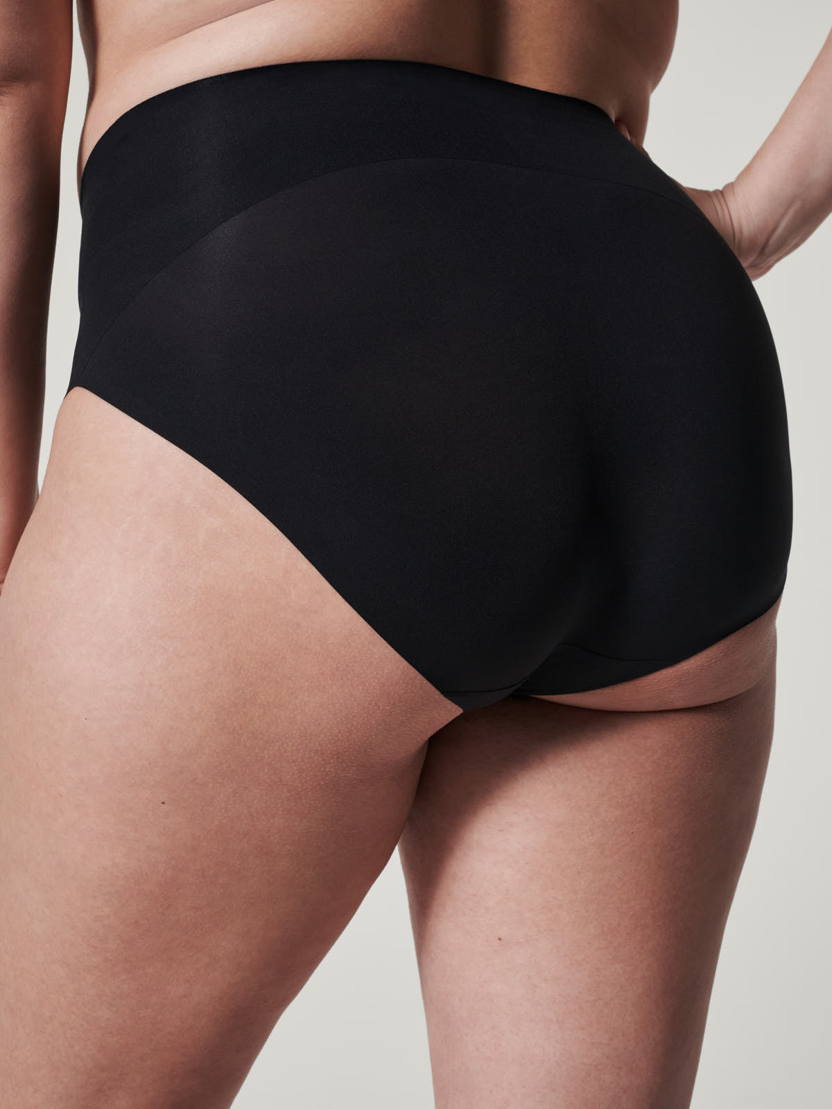 Black seamless SPANX Undie-Tectable® Brief by Spanx shown on a model from the back, highlighting smooth fit.