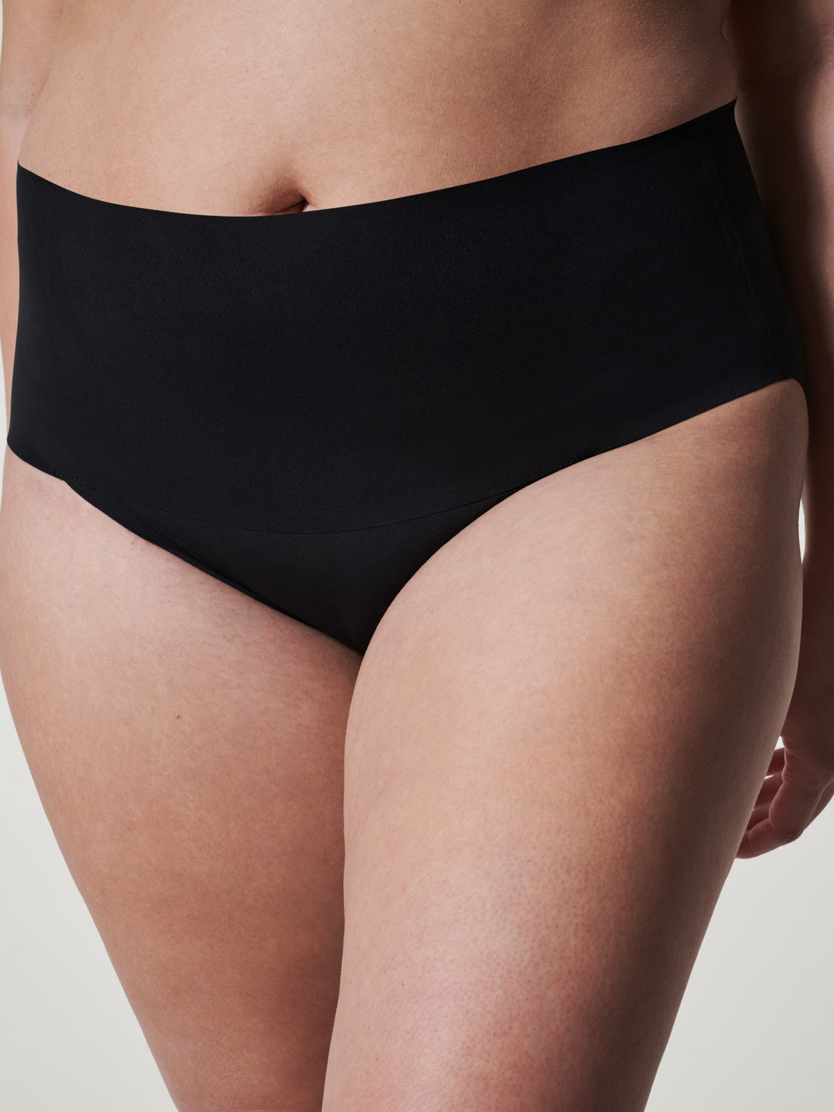 Close-up of a person wearing black SPANX Undie-Tectable® Brief underwear by Spanx, smooth seamless design.