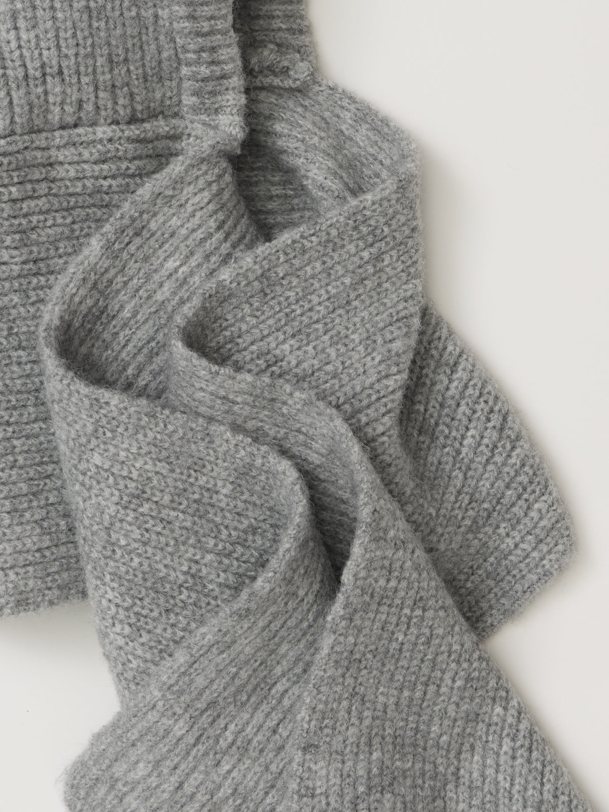 Close-up of a gray knitted sweater with ribbed trim and textured fabric folds