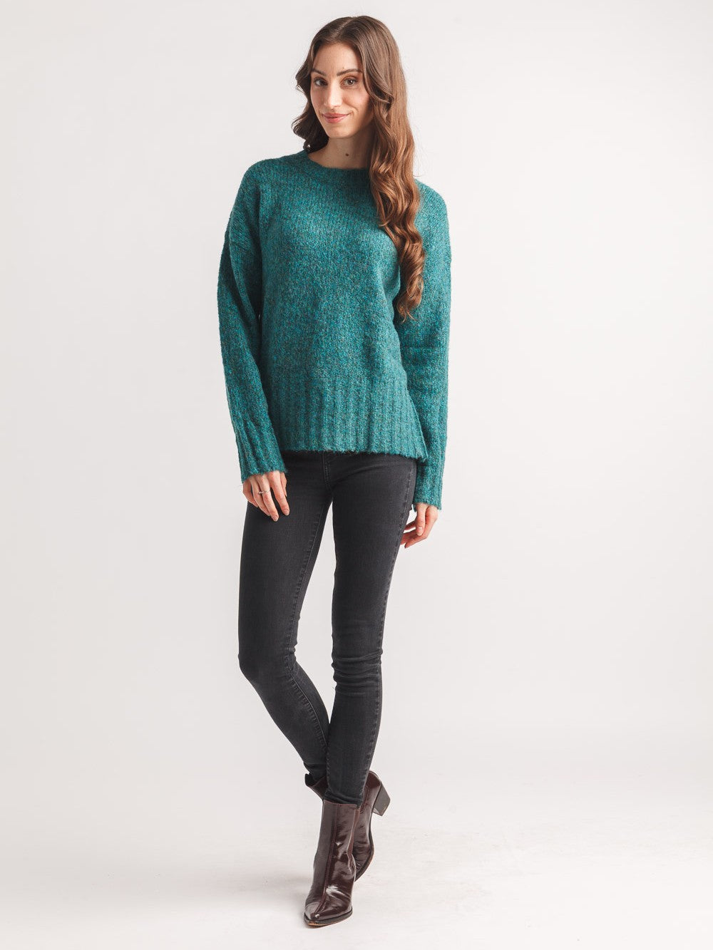 Model in Papillon Denim Teal Pepper Crew Neck Sweater paired with black skinny jeans and brown ankle boots by Papillon