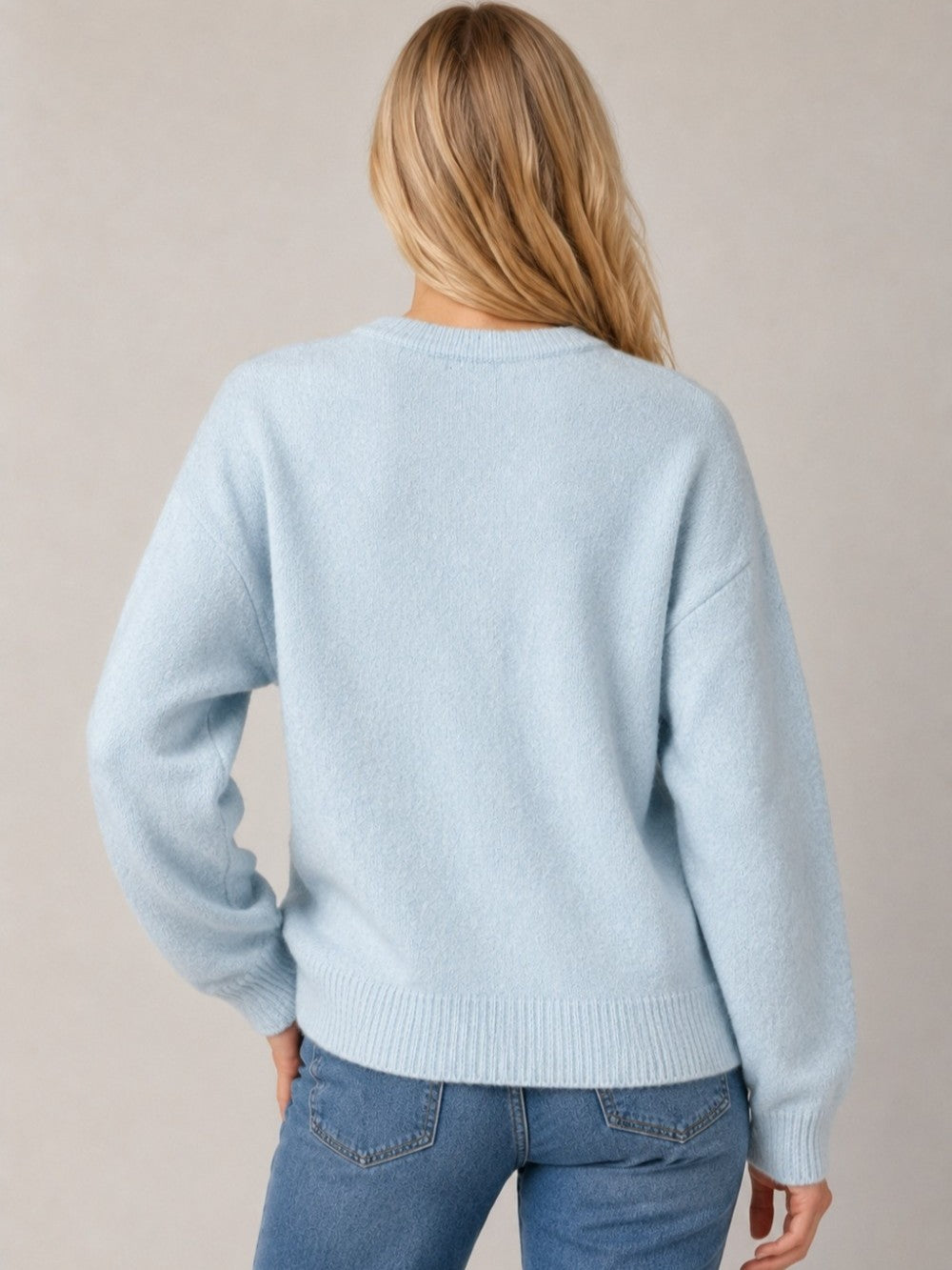 Back view of a light blue knit sweater with jeans and long blonde hair visible