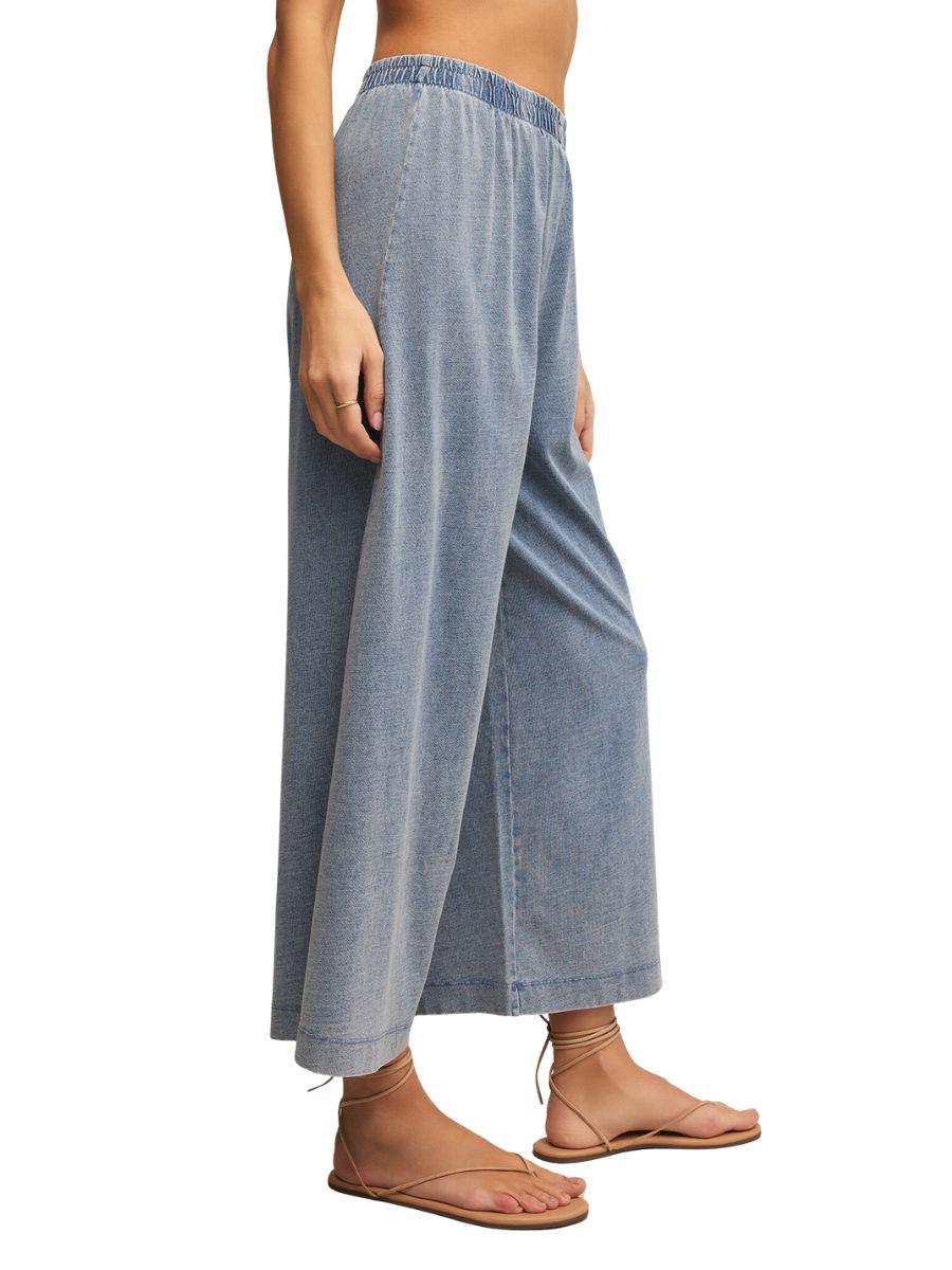 Light blue wide-leg denim pants with elastic waistband and tan lace-up flat sandals on feet