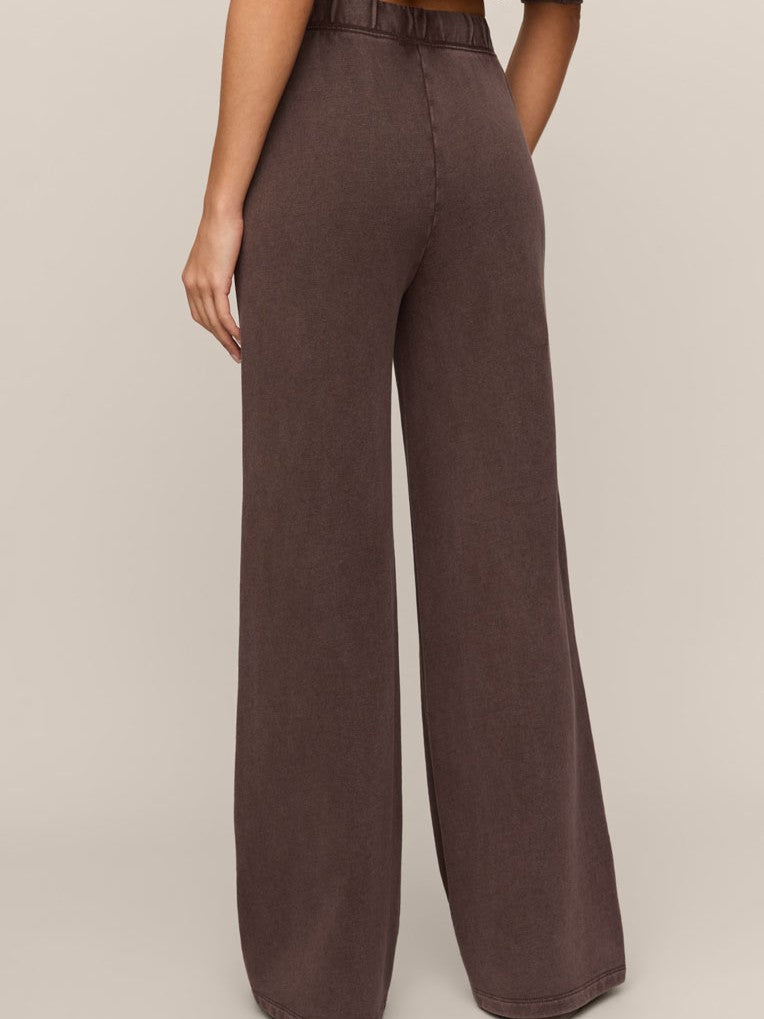 Back view of wide-leg brown pants with an elastic waistband against a plain beige background.