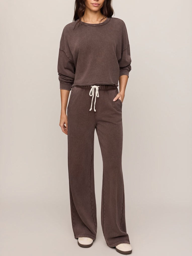 Brown long-sleeve top and matching drawstring pants with relaxed fit, styled with white slip-on shoes.