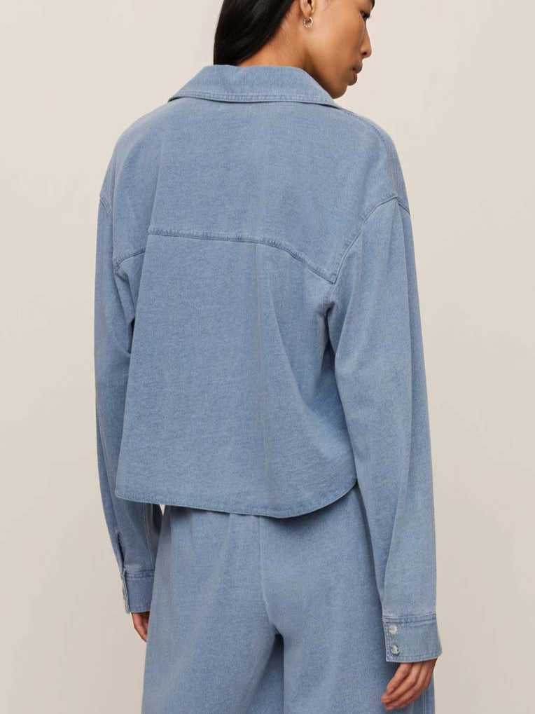 Light blue denim jacket shown from the back with long sleeves and buttoned cuffs paired with matching pants